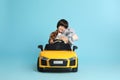 Little child with toy driving car on light blue background Royalty Free Stock Photo