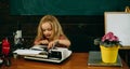 Little child type on typewriter at desk. Girl learn typing on retro typewriter in school