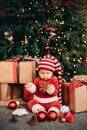 Little child under Christmas tree. baby girl in Santa Claus hat with gifts under Christmas tree Royalty Free Stock Photo