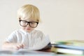 Little child wearing glasses is having fun with a book. Cute boy is watching pictures and learning letters. Preparation for school Royalty Free Stock Photo