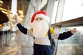 Little child wearing Santa Claus hat on background of an international airport. Preschooler boy is waiting for a merry Christmas.