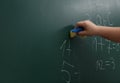 Little child wiping math sums from chalkboard, closeup.