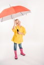 little child in yellow raincoat with umbrella