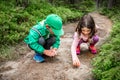 Little children boy and girl sitting on forest ground exploring and learning about nature and insects. Looking at a black bug. Royalty Free Stock Photo