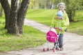 Little children brother and sister are driving a toy baby carriage in park Royalty Free Stock Photo