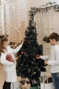 Little children decorate the Christmas tree in a bright interior. Girl and boy, brother and sister hang New Year`s toys Royalty Free Stock Photo