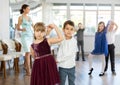 Little children in elegant dresses practicing waltz dance in school hall