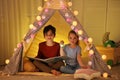 Little children with flashlight reading book in play tent Royalty Free Stock Photo