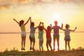 Little children jumping near river at sunset, back view Royalty Free Stock Photo