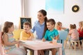 Little children with kindergarten teacher drawing at table indoors