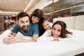 Little children lie on the backs of young happy parents in a mattress store. Royalty Free Stock Photo