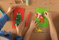 Little children making beautiful Christmas greeting cards at wooden table, top view Royalty Free Stock Photo