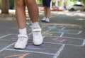 Little children playing hopscotch drawn with chalk on asphalt outdoors, closeup Royalty Free Stock Photo