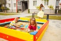 Little children playing at modern sandbox with toys. Young happy family on a walk. Royalty Free Stock Photo