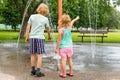 Little children playing at water splash pad fountain in park playground on hot summer day Royalty Free Stock Photo