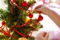 Little children`s pen hangs a red ball on a decorated Christmas tree