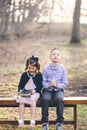 Little Christian boy praying and a girl holding the holy bible while sitting on a bench in a park Royalty Free Stock Photo