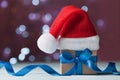 Little christmas gift box or present and santa hat against magic bokeh background. Holiday greeting card. Royalty Free Stock Photo
