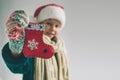 Little christmas sock in hands at the girl. The child is dressed in sweater, christmas hat and scarf studio shot Royalty Free Stock Photo