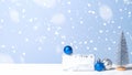 Little Christmas tree with gift box and balls in snow on blue background. Christmas, New Year, winter holidays concept Royalty Free Stock Photo