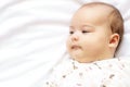 Little chubby newborn baby in a white bodysuit lying on the bed. Top view of a newborn baby on a white warm blanket. The Royalty Free Stock Photo