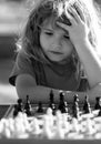 Little clever boy thinking about chess. Little boy playing chess outdoor in park. Close up face of clever smart child.