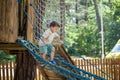 Little climber takes the rope bridge. Boy has fun time, kid climbing on sunny warm summer day Royalty Free Stock Photo