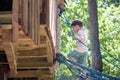 Little climber takes the rope bridge. Boy has fun time, kid climbing on sunny warm summer day