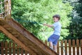 Little climber takes the rope bridge. Boy has fun time, kid climbing on sunny warm summer day