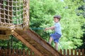 Little climber takes the rope bridge. Boy has fun time, kid climbing on sunny warm summer day Royalty Free Stock Photo