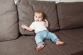 Little contented happy baby boy with pacifier sitting on a bed or a sofa Royalty Free Stock Photo