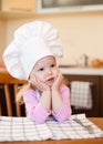 Little cook girl sitting at kitchen table waiting Royalty Free Stock Photo