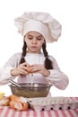 Little cook girl in a white apron breaks eggs in a deep dish Royalty Free Stock Photo