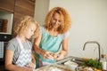 Woman and cute daughter cooking on kitchen, making dough for birthday party. Royalty Free Stock Photo