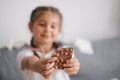 Little crafty girl eats sweets at home. Kid eating chocolate and have fun. Chaos at home. Focus on hands Royalty Free Stock Photo