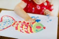 Little creative toddler girl painting with finger colors a fish. Active child having fun with drawing at home, in Royalty Free Stock Photo
