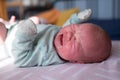 Little crying caucasian newborn baby on her bed suffering from colic Royalty Free Stock Photo