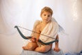 Little cupid toddle boy, holding bow and arrow, beautiful blond cherub