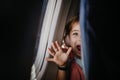 Little curious girl looking through seat in airplane.