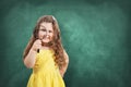 Little curious school girl with magnifier on chalkboard