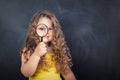 Little curious school girl with magnifier on chalkboard