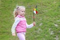 Little curly blonde girl holding multicolored pinwheel in her ha