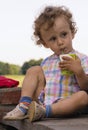 Little curly boy with juice in hands
