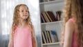 Little curly girl coquetting in front of mirror, dreaming to become adult, child Royalty Free Stock Photo