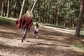 Happy, stylish little curly girl is running with her beautiful mother in forest.