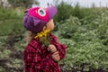 A little curly-haired girl in a colored cap and a red plaid shirt stands in the park and holds a bunch of yellow forest Royalty Free Stock Photo