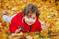 Little curly-haired girl lies on yellow maple leaves Royalty Free Stock Photo