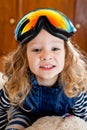 Little curly-haired girl in ski glasses sitting on a big teddy polar bear. Shot indoors Royalty Free Stock Photo