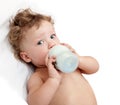 Little curly-headed baby sucks a bottle Royalty Free Stock Photo