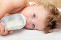 Little curly-headed baby sucks a bottle of milk Royalty Free Stock Photo